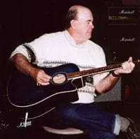 Man playing acoustic guitar on stage.