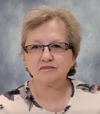 Smiling person wearing glasses against blue background.