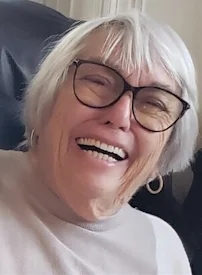 Smiling elderly woman with short white hair and glasses.