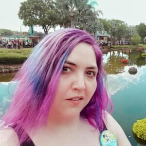 Person with colorful hair by a pond.