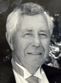 Elderly man smiling in formal attire, black and white