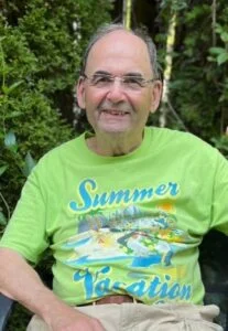 Smiling man in summer vacation shirt sitting outdoors.