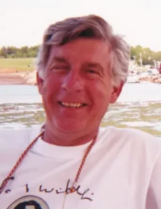 Smiling man outdoors near water and boats.