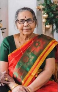 Elderly woman wearing a colorful saree and glasses.