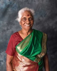 Smiling woman in green sari poses for photo.