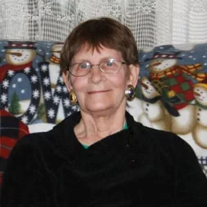 Smiling woman with glasses and Christmas decorations.