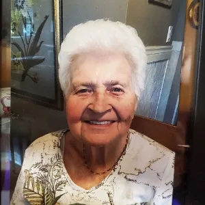 Elderly woman smiling at camera, floral shirt.