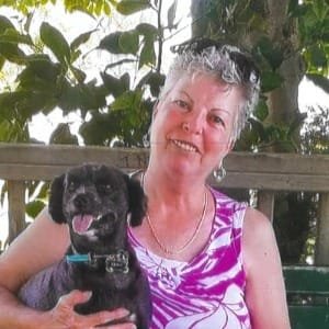 Woman smiling with black dog outdoors.