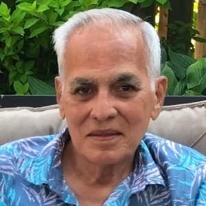 Elderly man sitting outdoors on a couch.