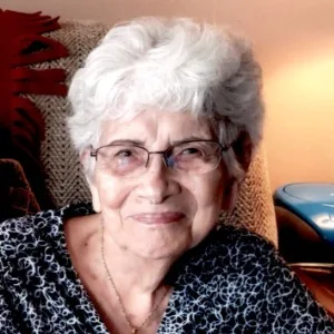 Smiling elderly woman with white hair and glasses.