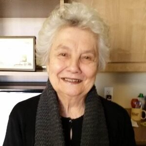 Smiling elderly woman with white hair and scarf.