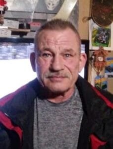 Man in a room with wall decorations and TV.