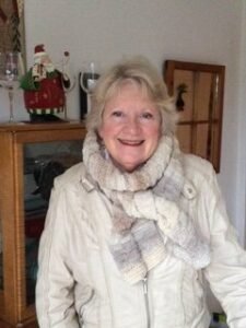 Smiling woman in cozy scarf and jacket indoors.