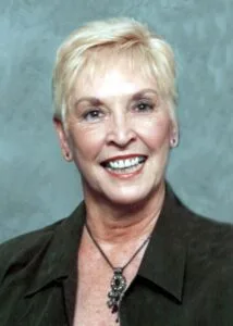 Smiling woman with short blonde hair.