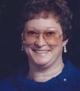 Smiling person wearing glasses and pearl earrings