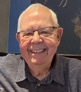 Smiling elderly man at a table indoors.