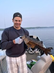 Man holding a large fish on a boat.