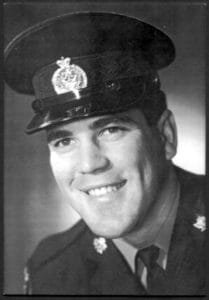 Smiling man in military uniform, black and white portrait.