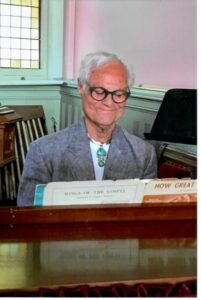 Elderly person playing piano in church setting.