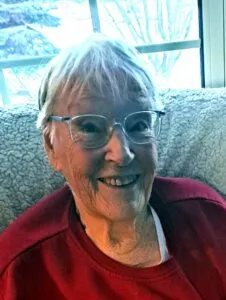 Smiling elderly woman with glasses by window