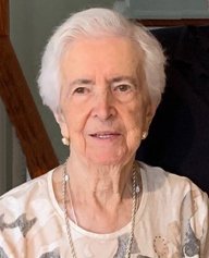 Elderly woman smiling, wearing a patterned shirt.