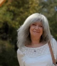 Smiling woman with gray hair outdoors.