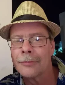 Man with glasses and straw hat smiling