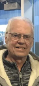 Smiling older man wearing glasses and a jacket.