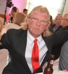 Man in suit with red tie at event.