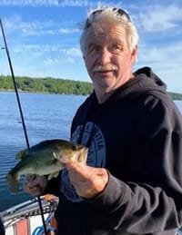 Man holding a fish by the lake.