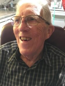 Elderly man smiling in a plaid shirt